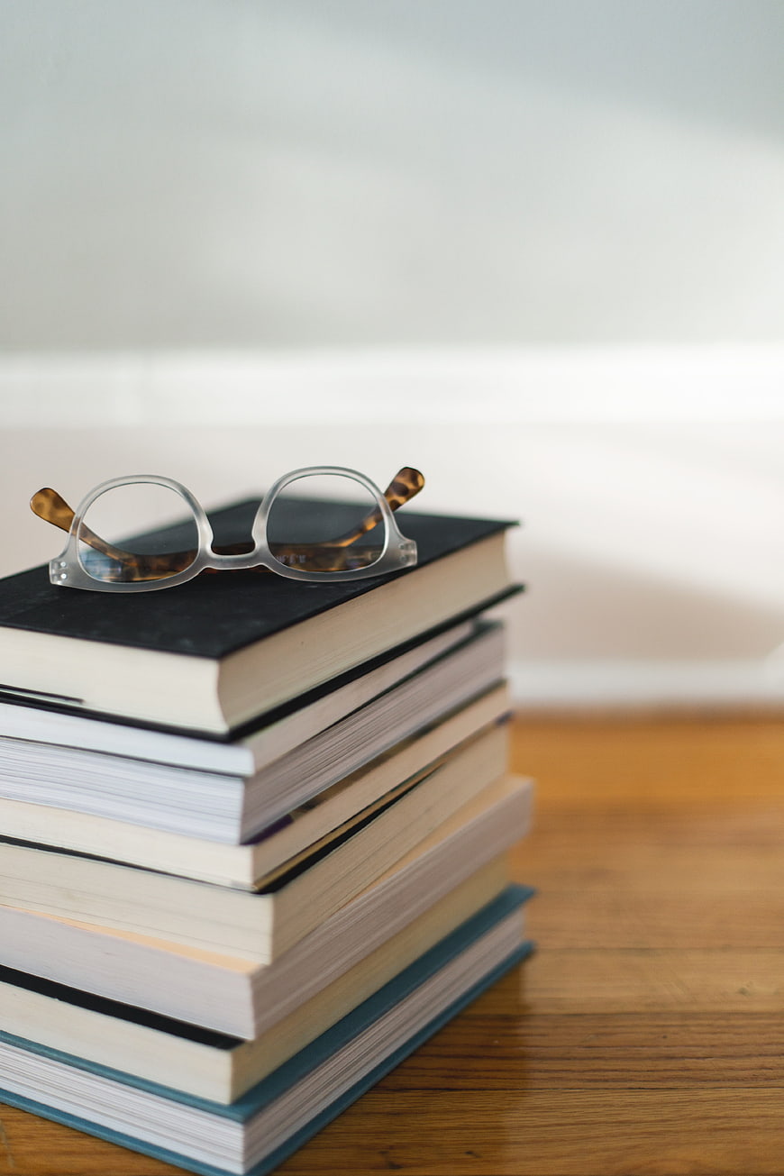 Reading Glasses Resting on a Stack of Hardcover Books