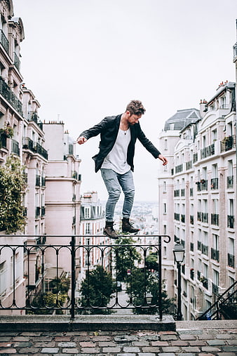 Man balancing on railing in Parisian urban setting
