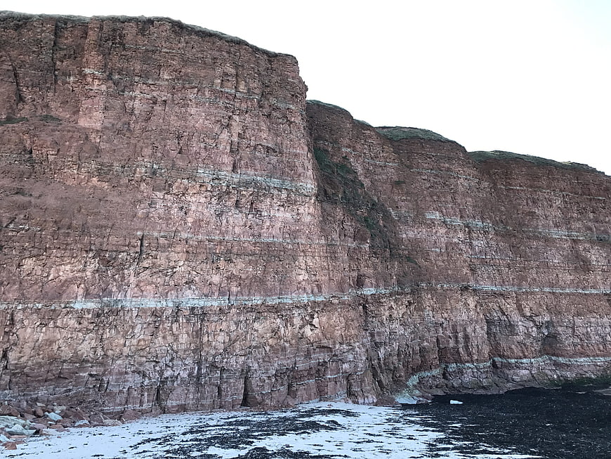 Red sandstone cliffs of Helgoland with snow-covered beach