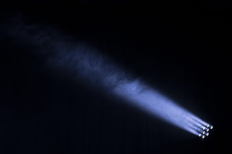 Blue spotlight beam cutting through dark smoke