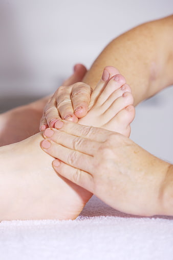 Close-up of hands performing foot massage on white towel