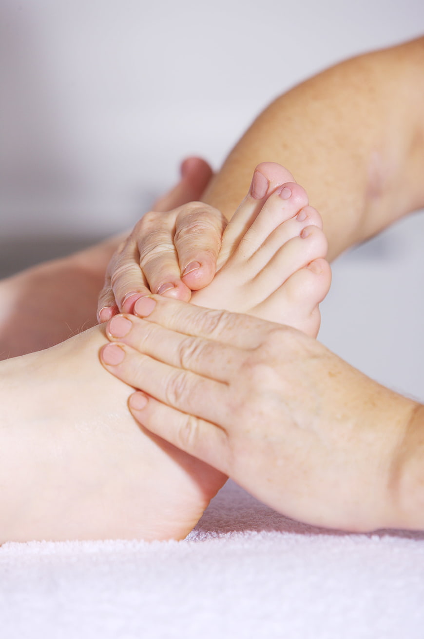 Close-up of hands performing foot massage on white towel