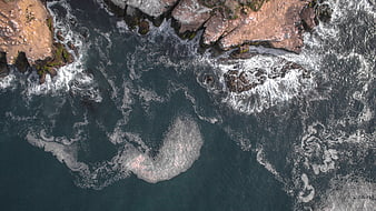 Aerial View of Ocean Waves Crashing Against Rocky Coastline