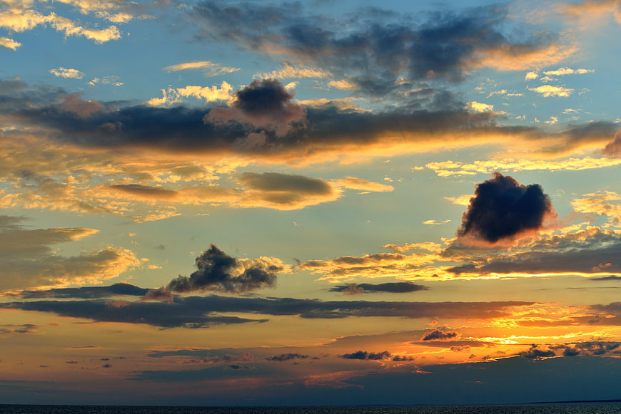Dramatic sunset sky with golden clouds over ocean horizon