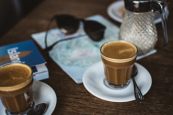 Two Flat White Coffees on Wooden Table with Map and Sunglasses