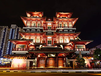 Illuminated Traditional Chinese Temple at Night with City Background