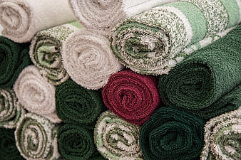 Stack of rolled green and beige towels with red accent