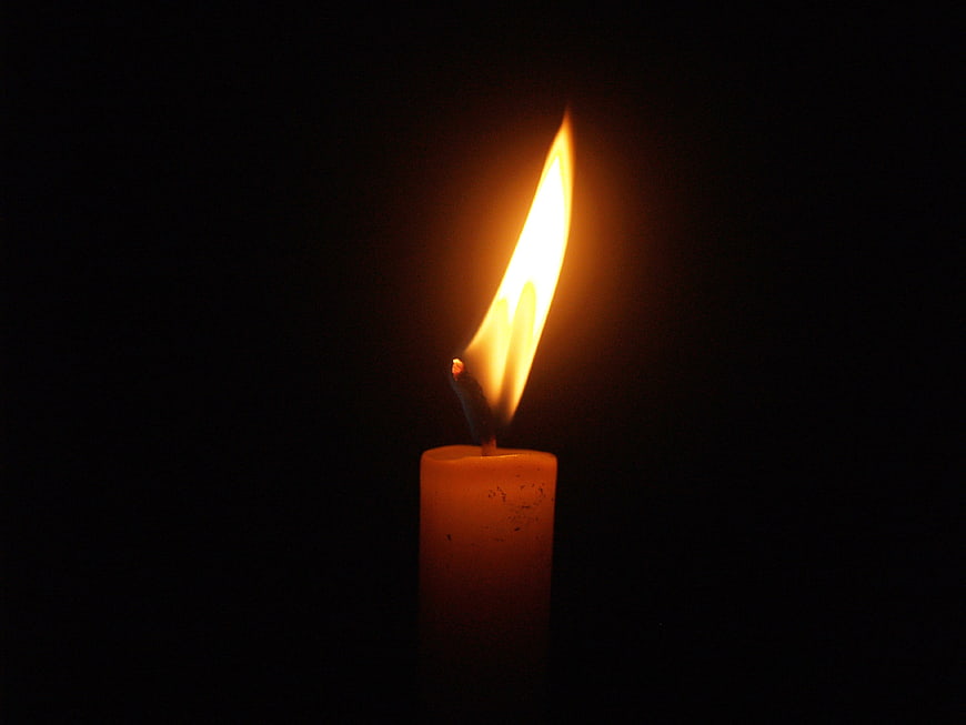 Single lit candle flame on black background