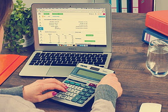Woman using calculator and laptop for accounting work