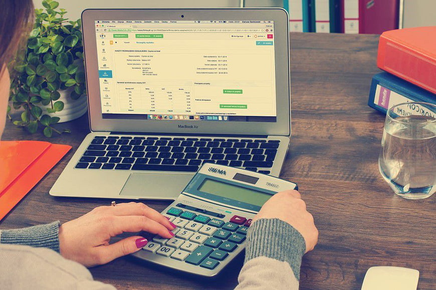 Woman using calculator and laptop for accounting work