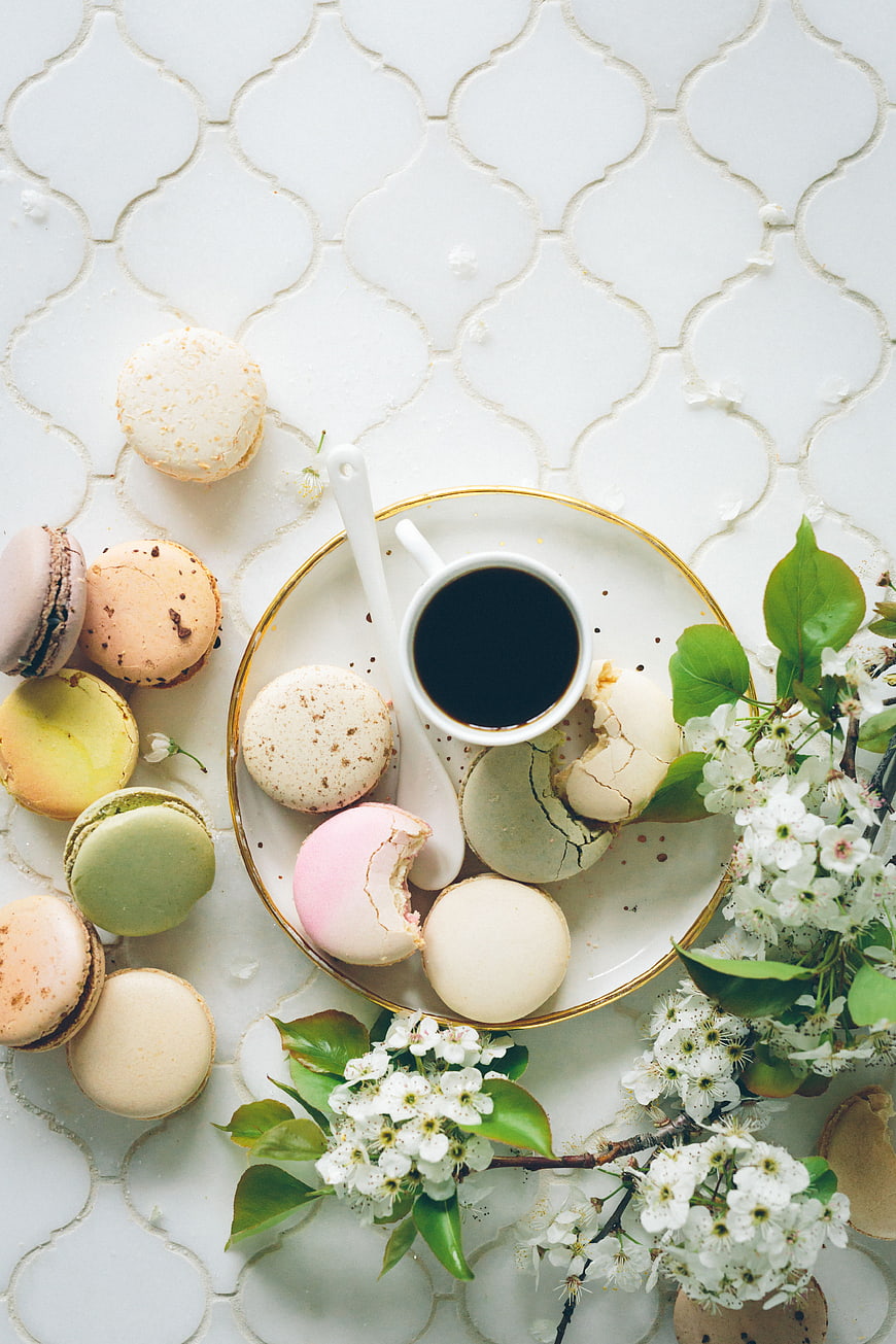 Pastel macarons and coffee with spring blossoms flat lay