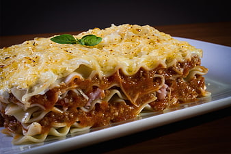 Close-up of layered lasagna with melted cheese and basil garnish