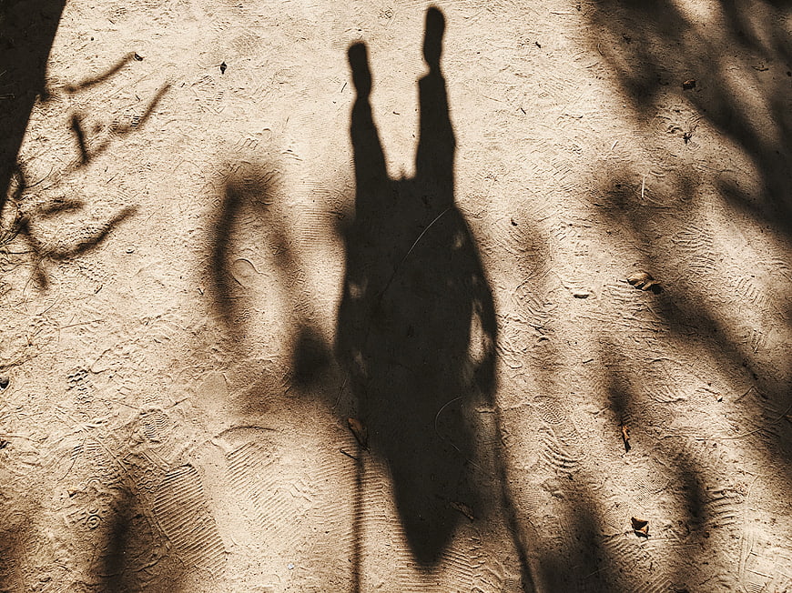 Shadow of person on sandy beach with swing silhouette