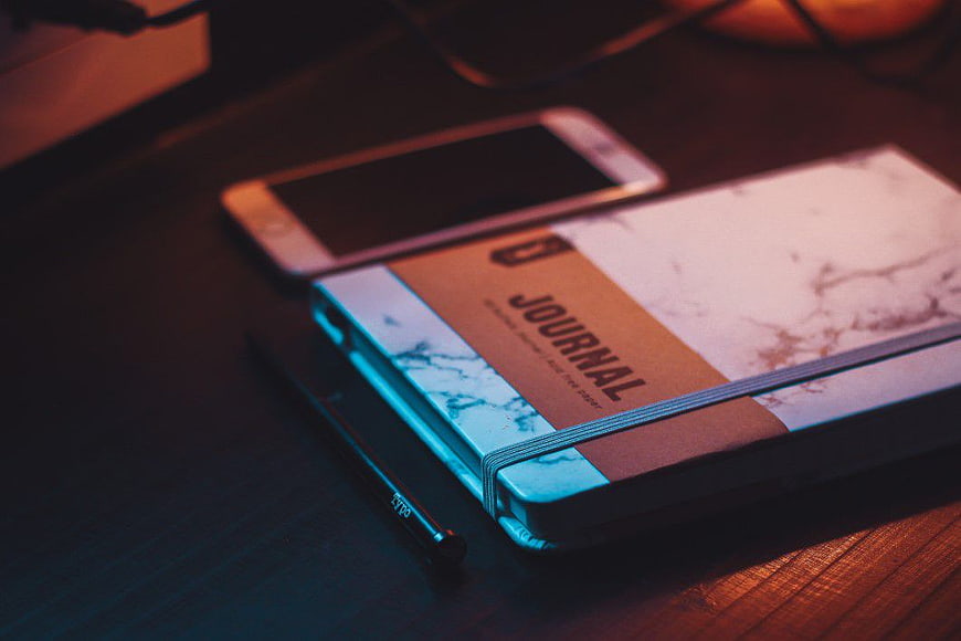 Journal and Smartphone on Wooden Desk with Neon Lighting