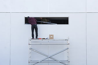 Construction workers installing window on modern white building facade
