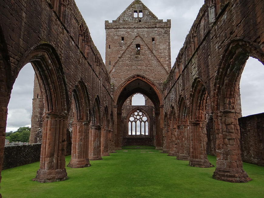 Interior of historic red sandstone abbey ruins with green lawn