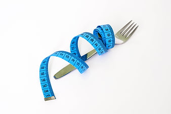 Blue measuring tape wrapped around silver fork on white background