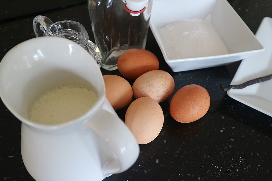 Baking ingredients with eggs, milk, and flour on black countertop
