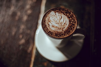 Overhead view of latte art coffee cup on wooden table