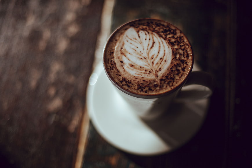 Overhead view of latte art coffee cup on wooden table