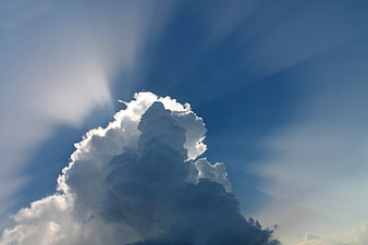 Dramatic cumulus cloud with sun rays in blue sky
