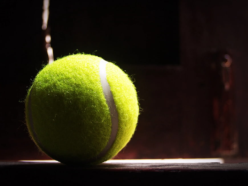 Close-up of a yellow tennis ball in dramatic lighting