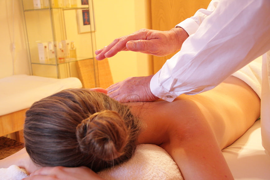 Therapist performing energy healing massage on woman's back