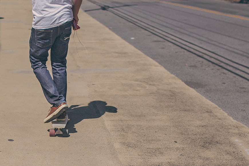 Man Skateboarding on Sidewalk with Large Copyspace