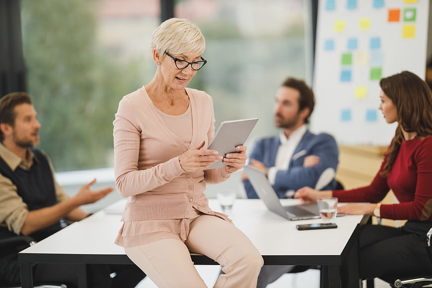 Senior Businesswoman Using Tablet in Office Meeting
