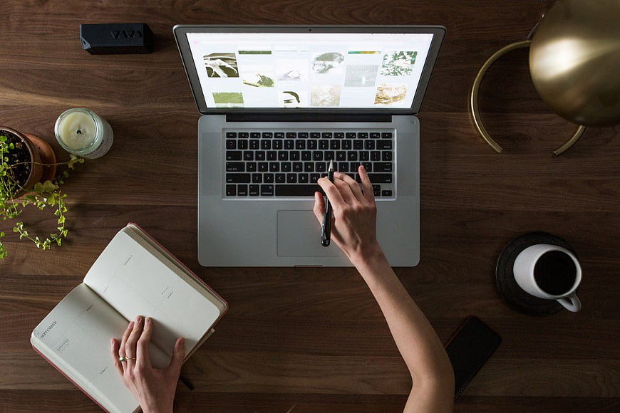 Overhead view of workspace with laptop, notebook, and coffee