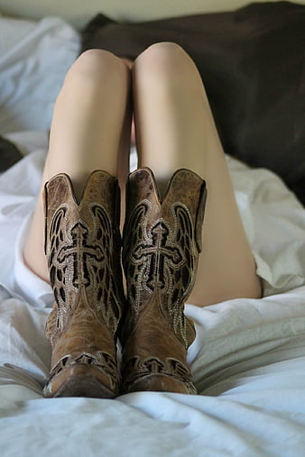 Woman's Legs Wearing Brown Leather Cowboy Boots on White Bedding