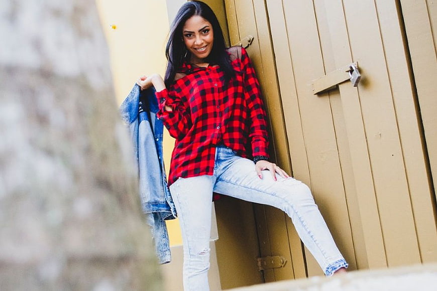 Stylish Woman in Red Plaid Shirt and Jeans Leaning Against Wall