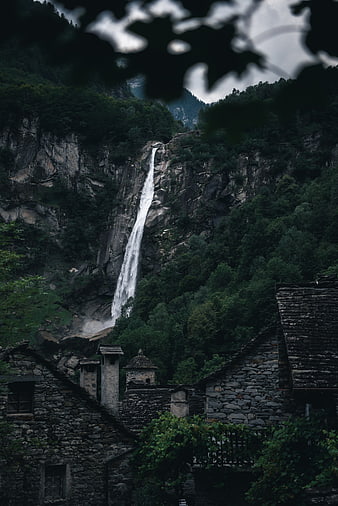 Dramatic waterfall cascading behind rustic stone village houses