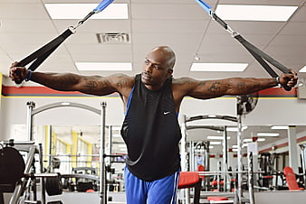 Athletic Black Man Training with Suspension Straps in Gym
