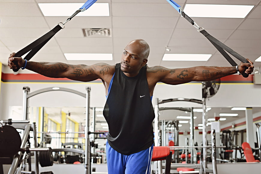 Athletic Black Man Training with Suspension Straps in Gym
