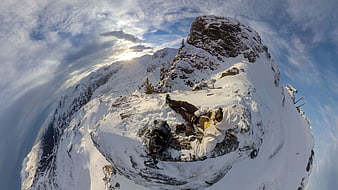 360-degree view of hiker resting on snowy mountain peak