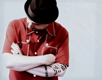 Man in Fedora and Red Shirt with Tattoos Looking Down
