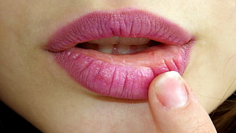 Close-up of pink lips with finger touching lower lip