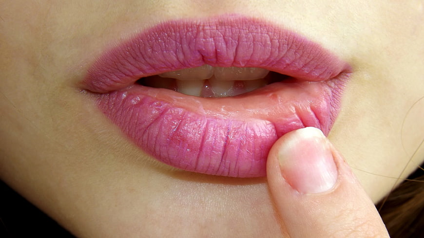 Close-up of pink lips with finger touching lower lip