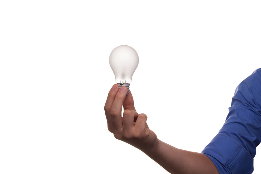 Hand holding light bulb on white background