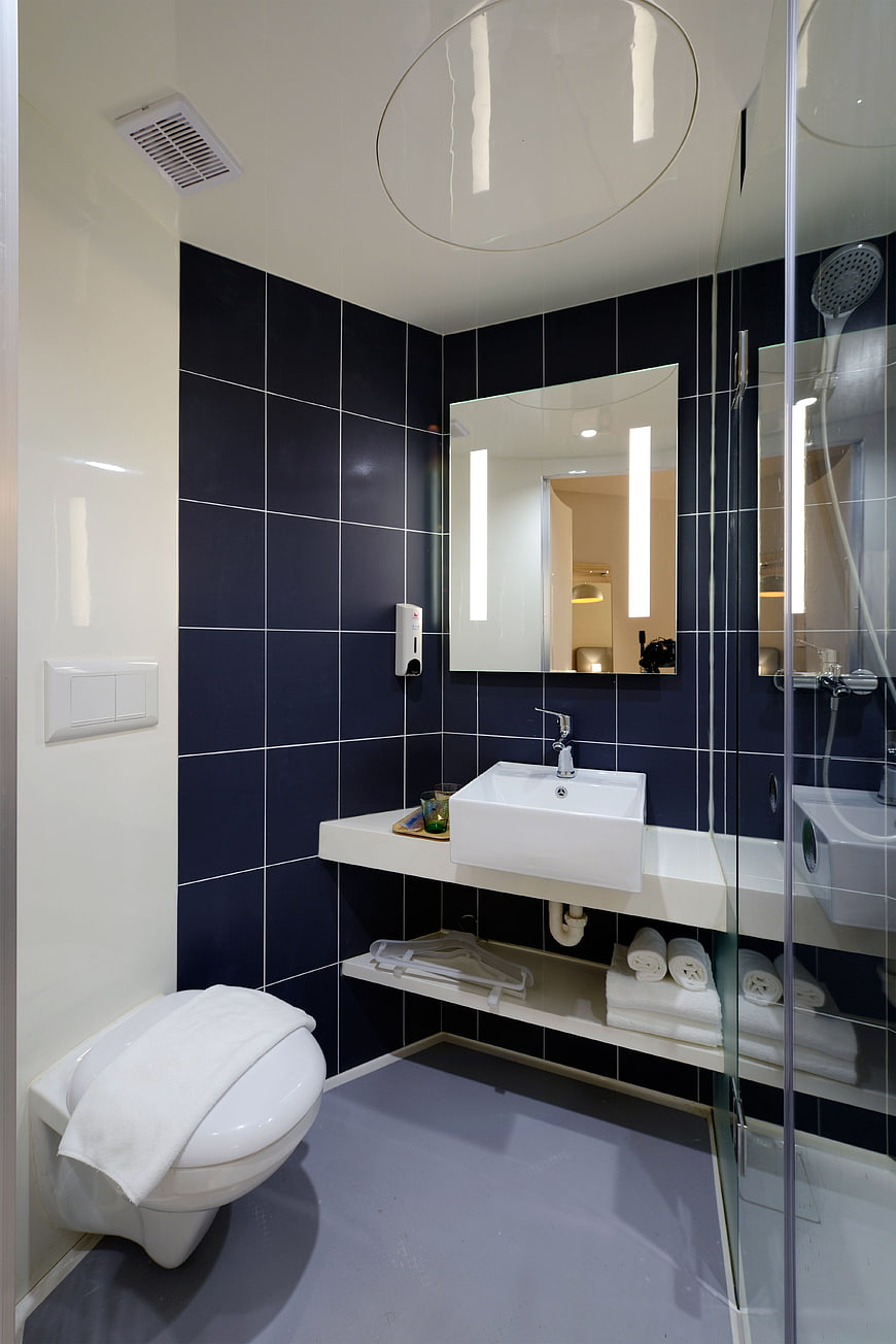 Modern Hotel Bathroom with Navy Blue Tiles and White Fixtures