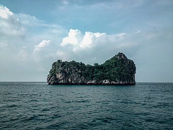 Lush Green Rocky Island in Blue Ocean with Clouds