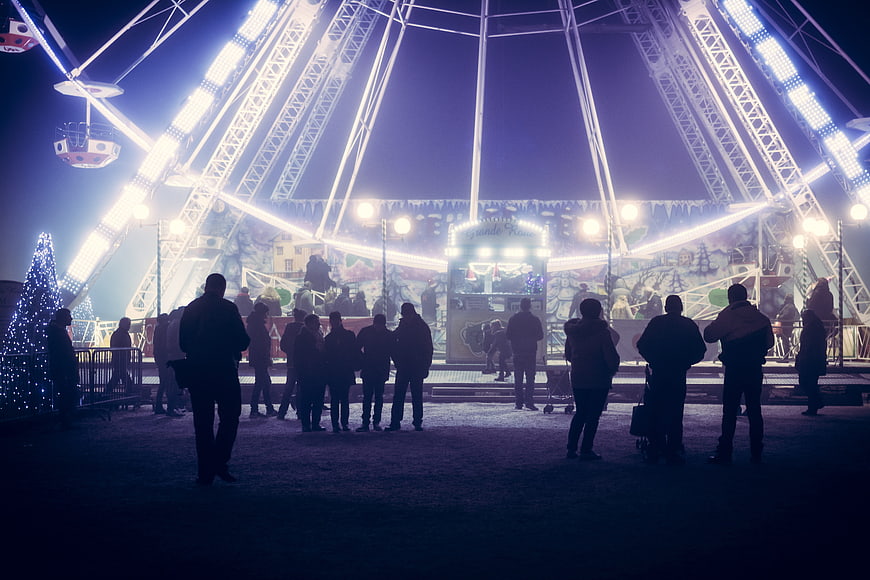Silhouetted Crowd At Nighttime Christmas Market Ferris Wheel