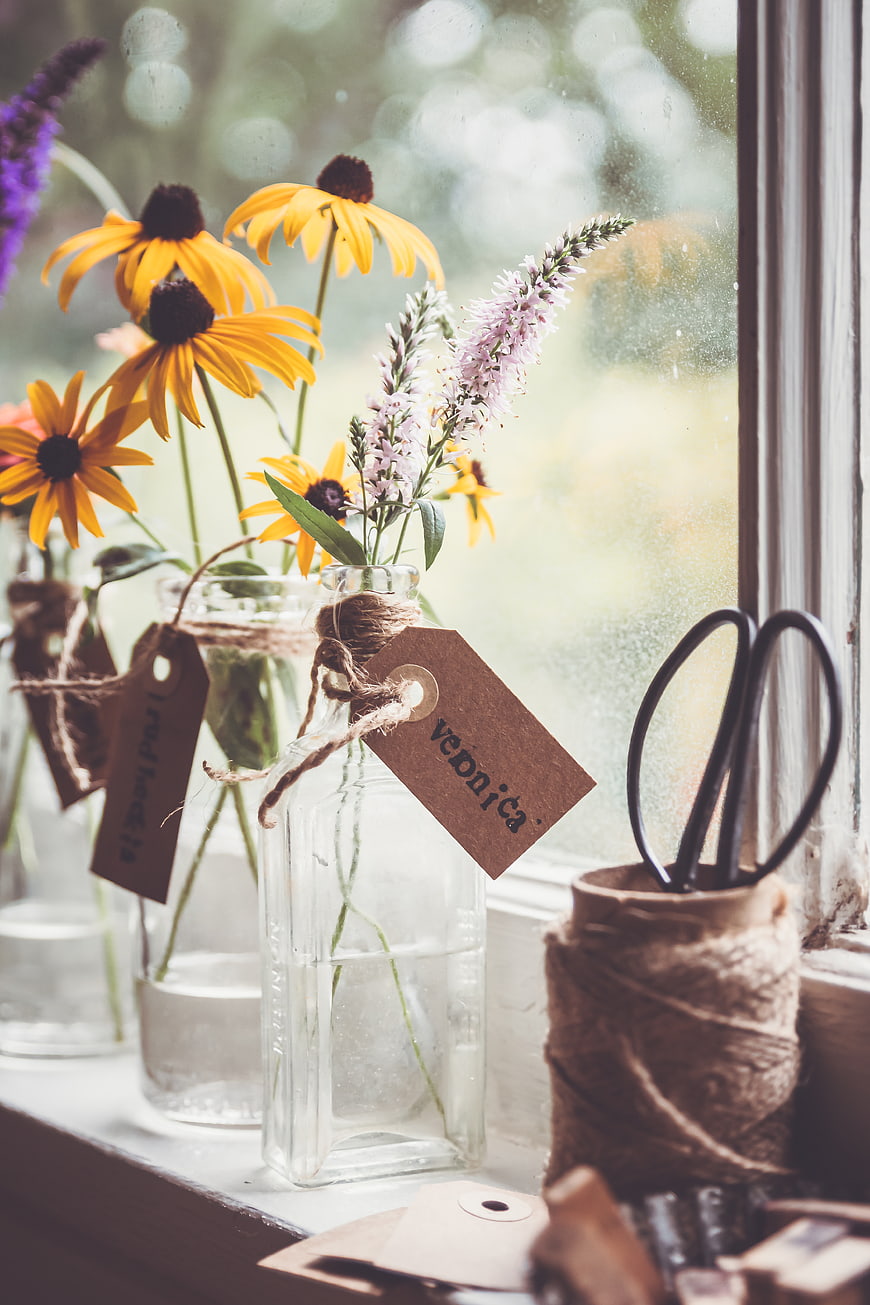 Rustic wedding favors with wildflowers in glass bottles on windowsill