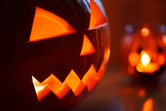 Close-up of glowing jack-o-lantern with candle light and bokeh background
