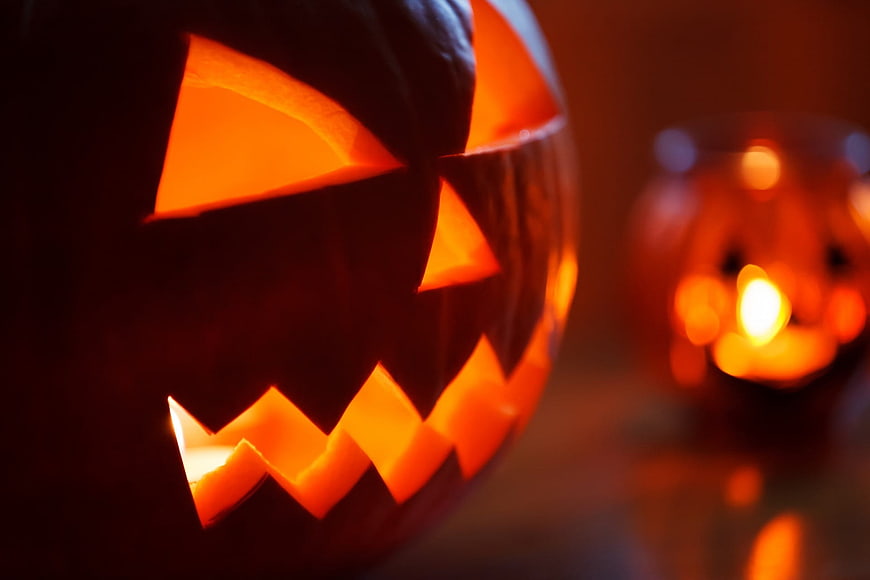 Close-up of glowing jack-o-lantern with candle light and bokeh background