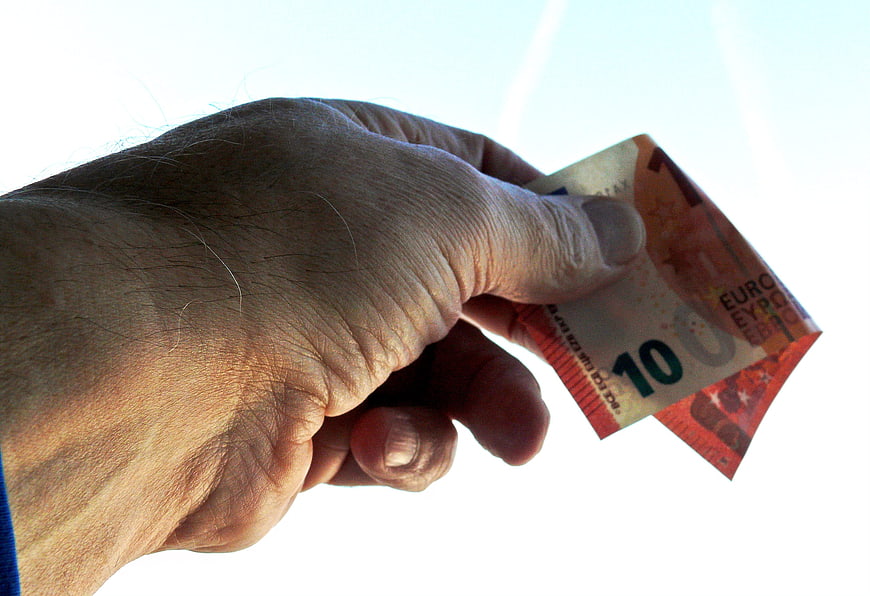 Hand holding ten euro banknote against white background