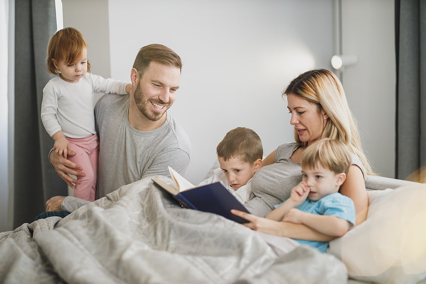 Happy family reading bedtime story together in bed