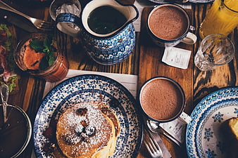 Overhead view of pancakes and hot chocolate on rustic wooden table
