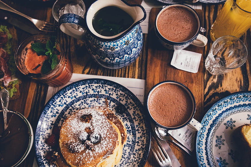 Overhead view of pancakes and hot chocolate on rustic wooden table